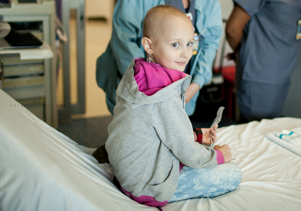 Girl sitting on a hospital bed with doctors in the background
