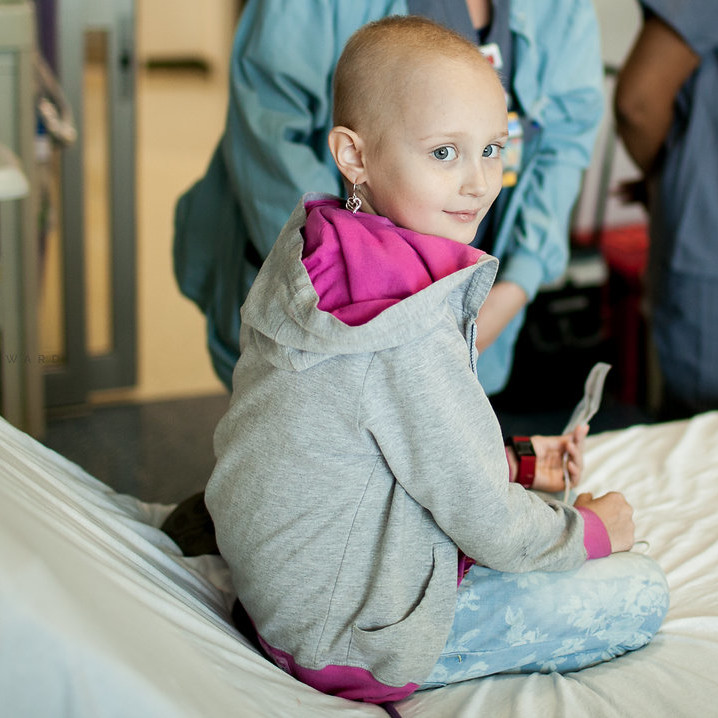 Girl sitting on a hospital bed with doctors in the background