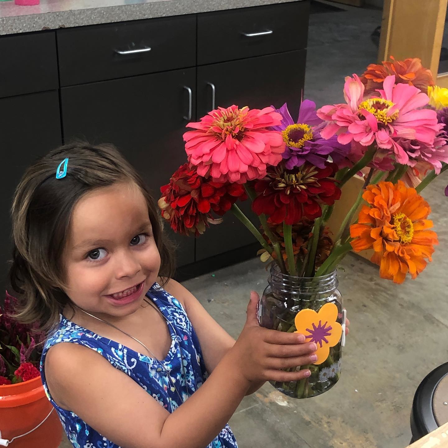 A little girl holding a mason jar full of flowers