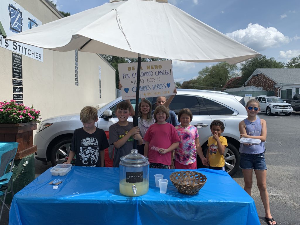 8 kids standing under a tent at their lemonade stand benefiting Connors Heroes