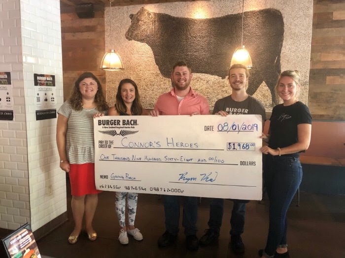 Burger Bach presents a check to Celia for Connors Heroes