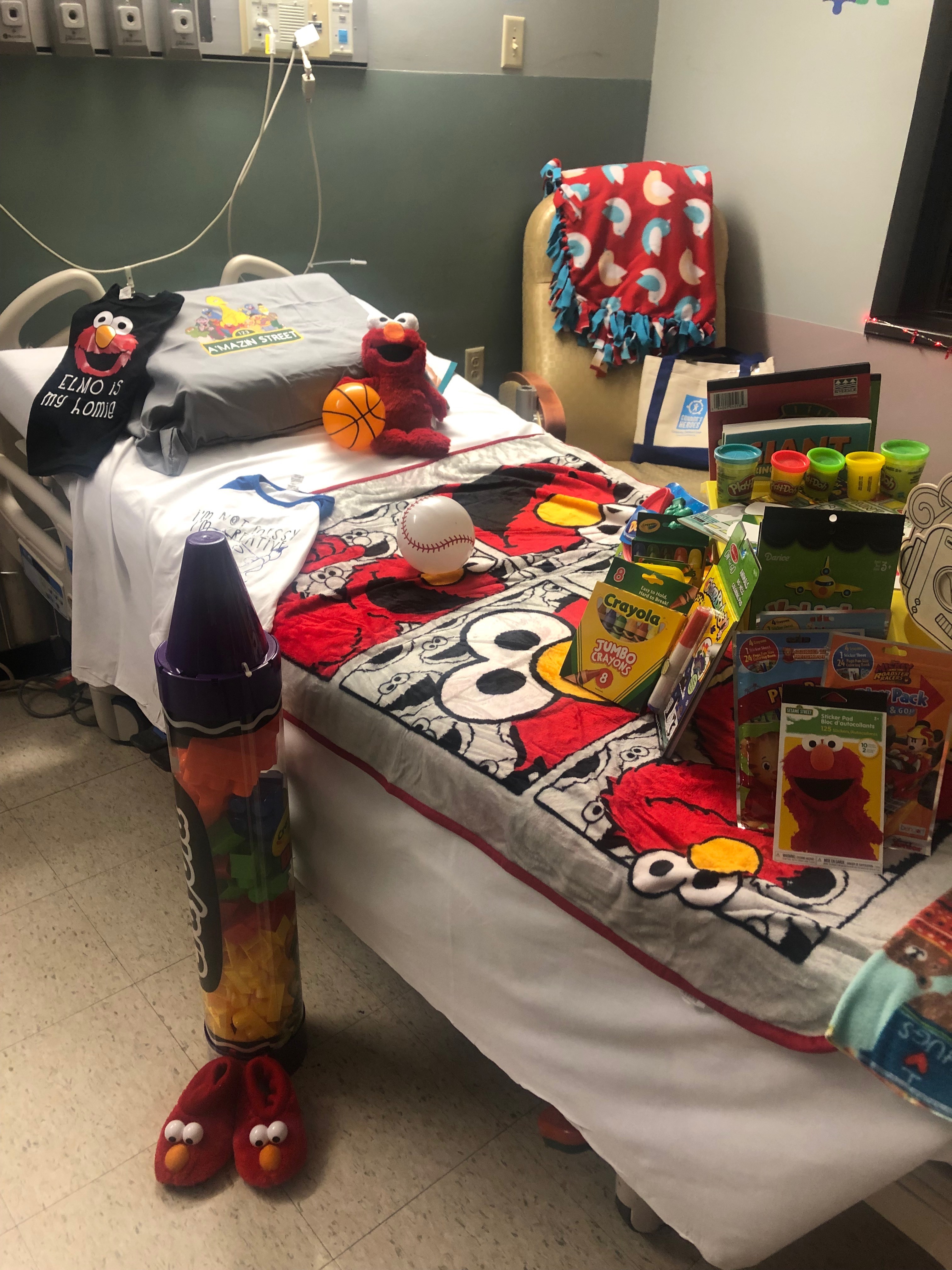 Hospital bed covered with Elmo blanket and Elmo coloring books
