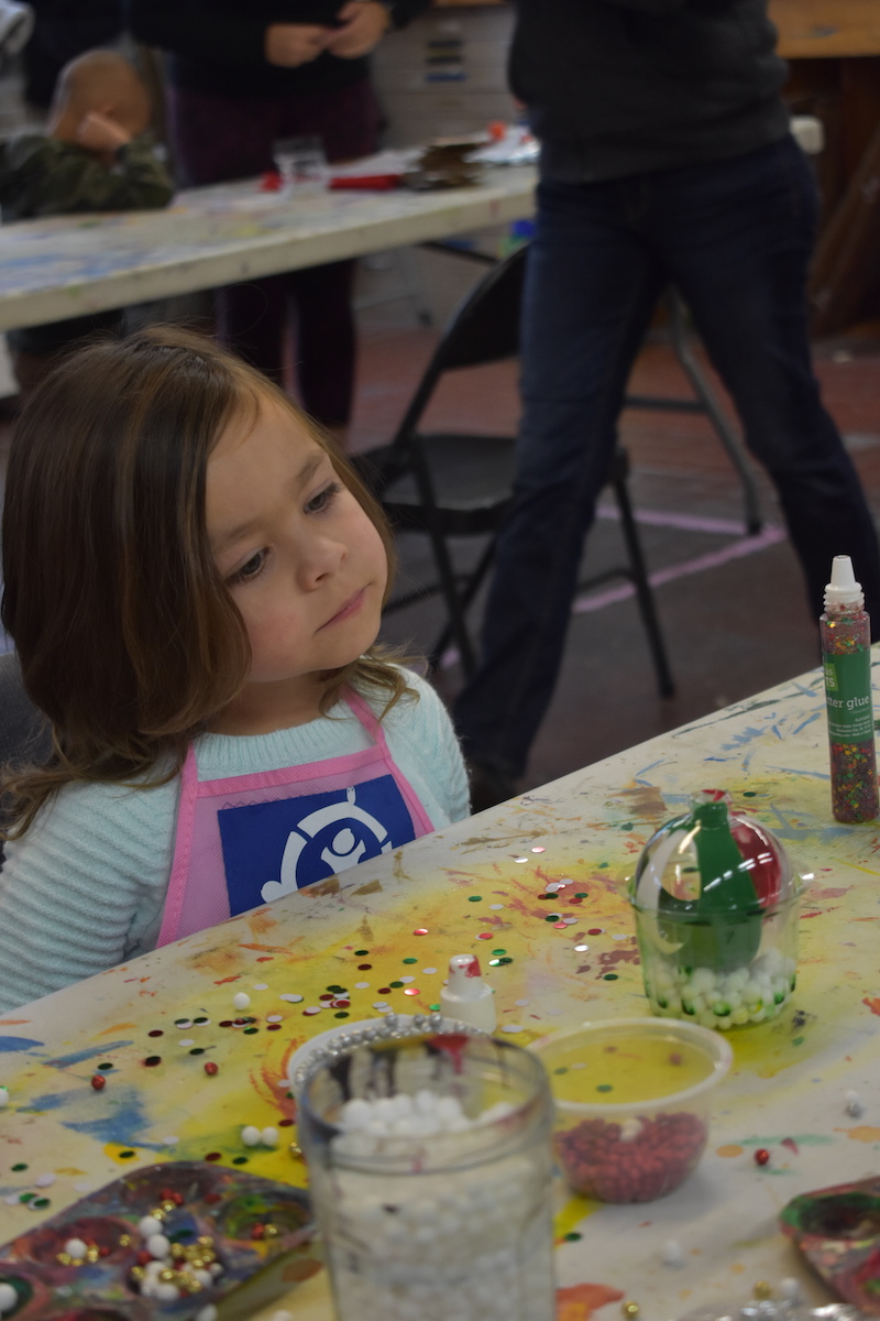 Girl looking at an ornament she made at the Heroes Art Session