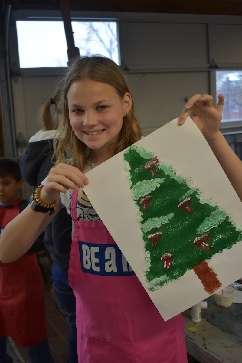 Teen holding a picture she painted of a Christmas tree