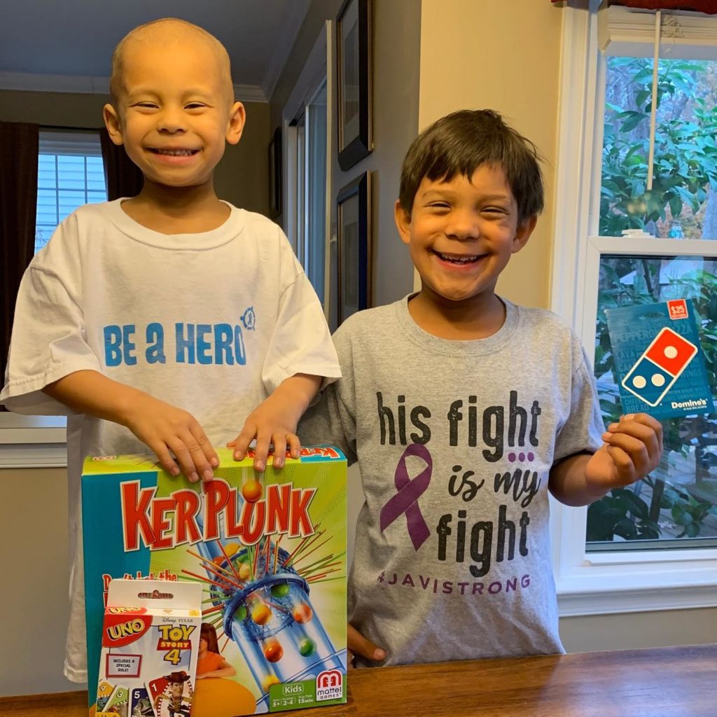 Two brothers smiling holding board games and a pizza gift certificate