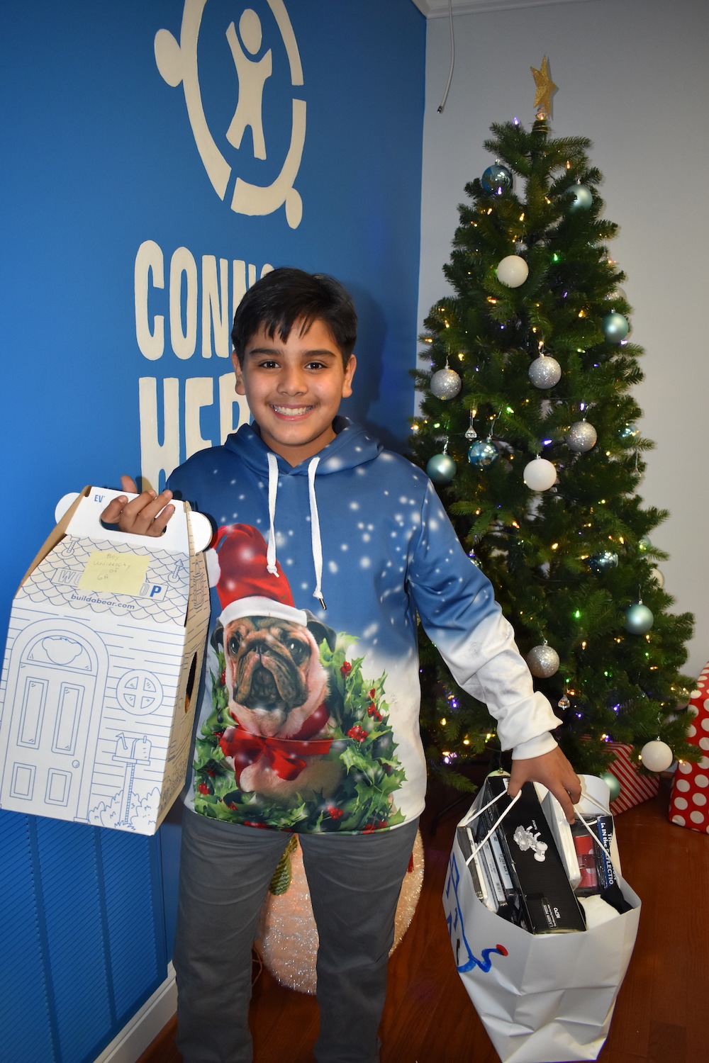 A teen holding a box and a gift bag full of presents