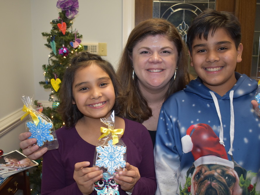 Two children with a woman holiday snowflake shaped cookies
