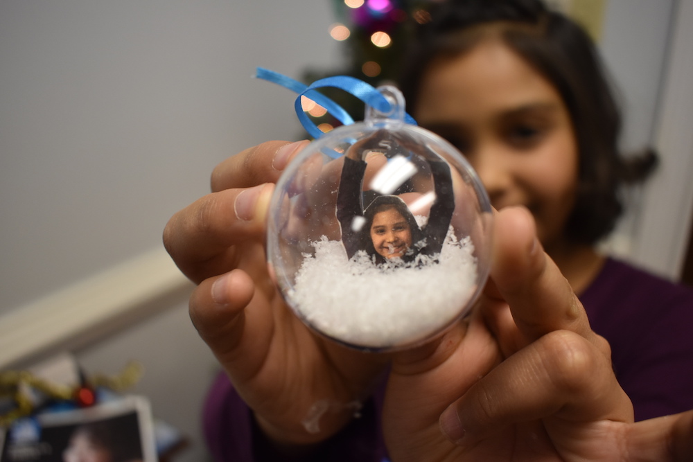 Child holding an ornament with her picture inside
