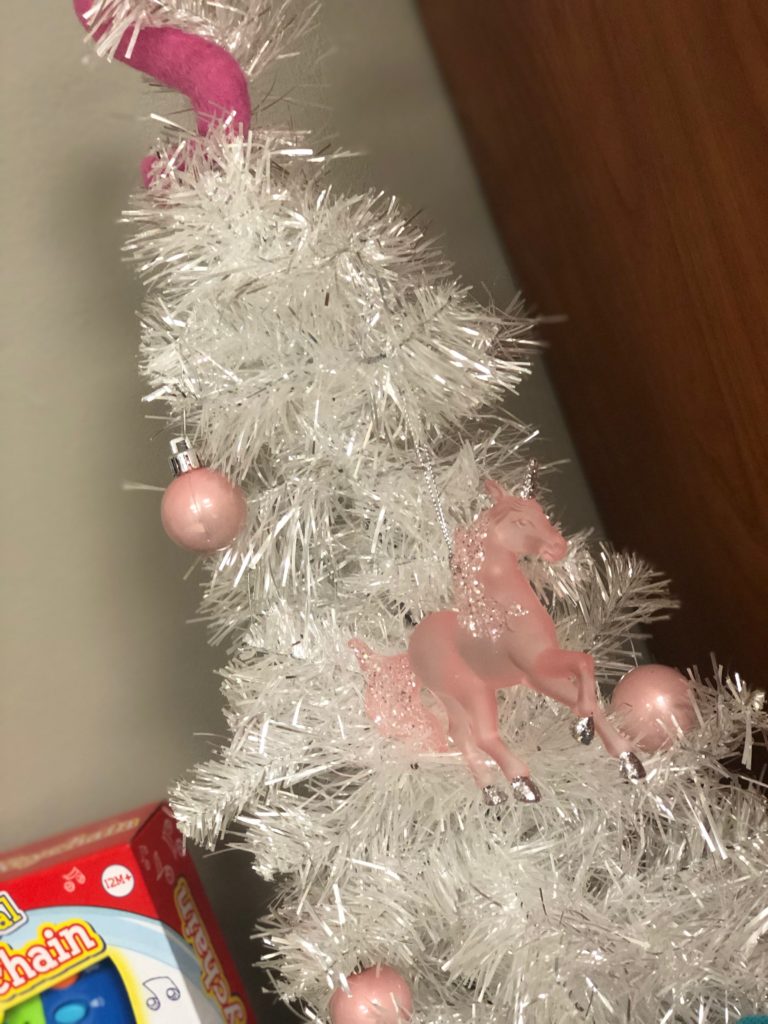 A white tree decorated with pink glass orbs and sparkly unicorns