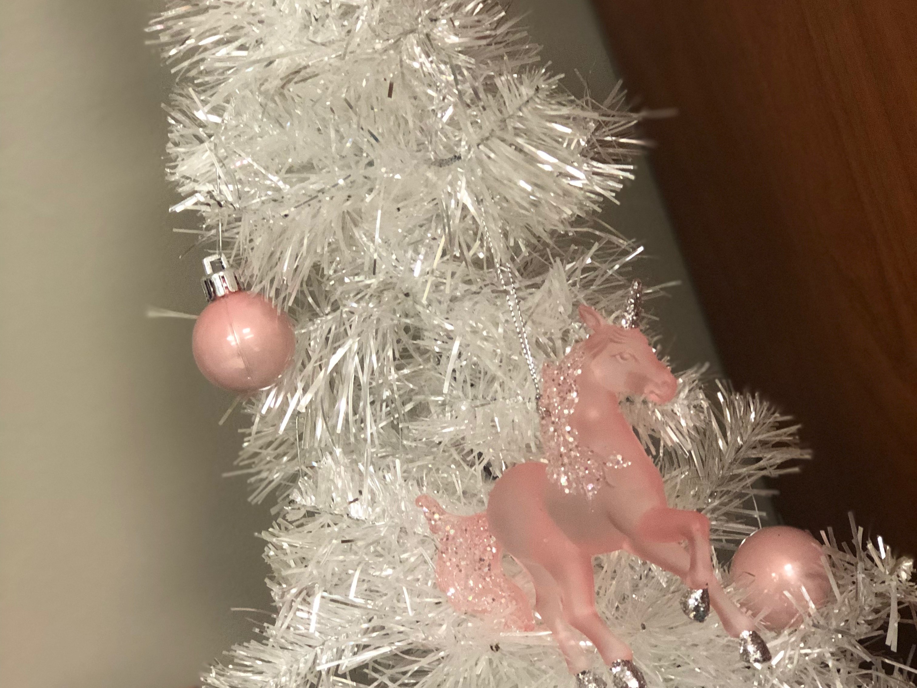 A white tree decorated with pink glass orbs and sparkly unicorns