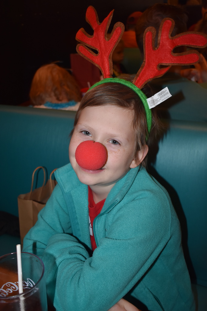 Girl wearing reindeer antlers and red nose