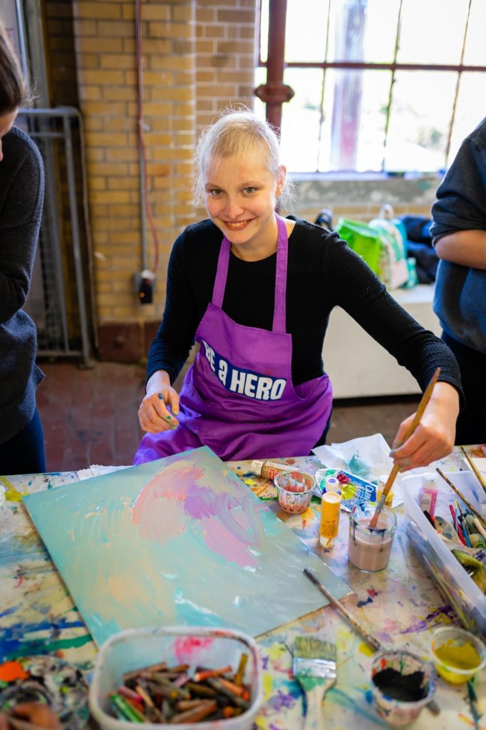 Teen smiles while working on her painting