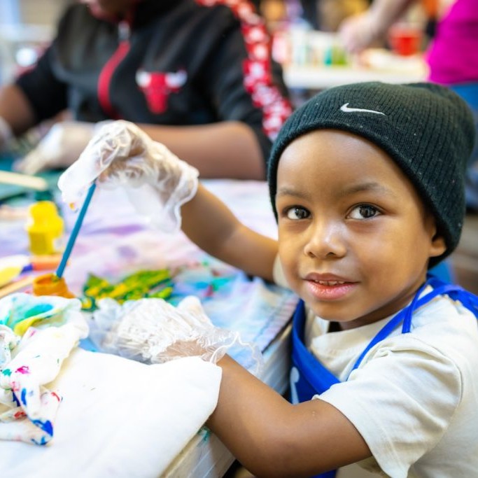 Child working on a craft and smiling at the camera