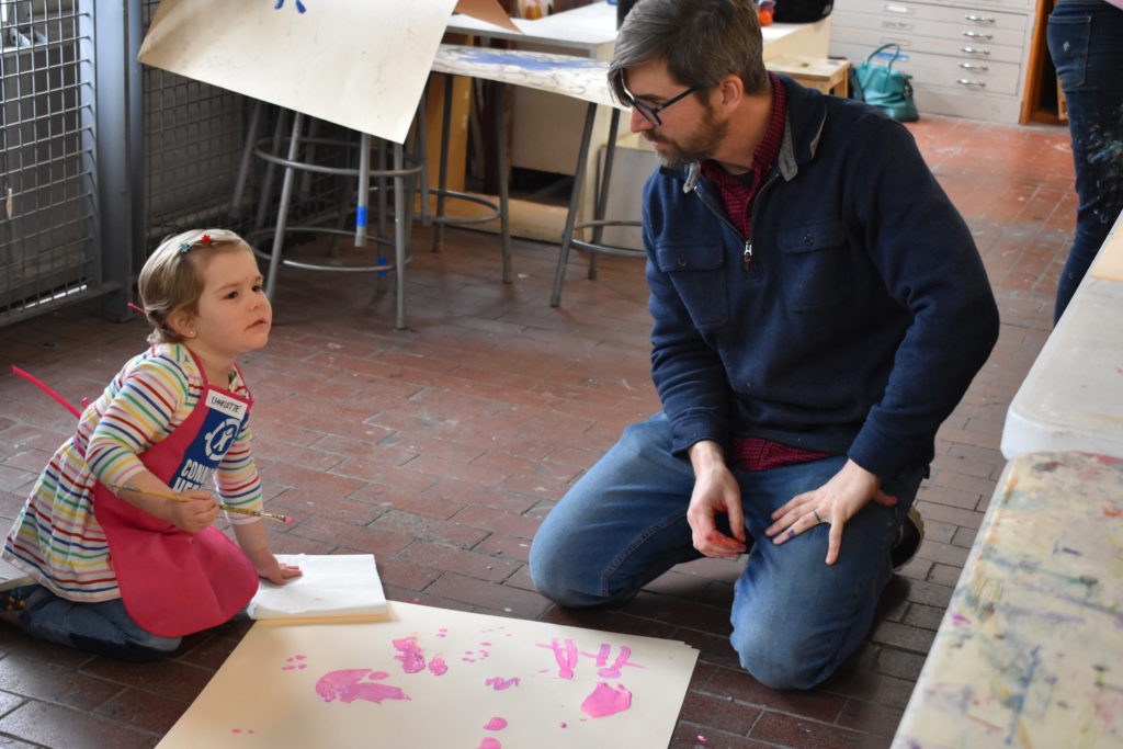 An artist and a girl paint pink on a canvas at the Connors Heroes Art Sessions