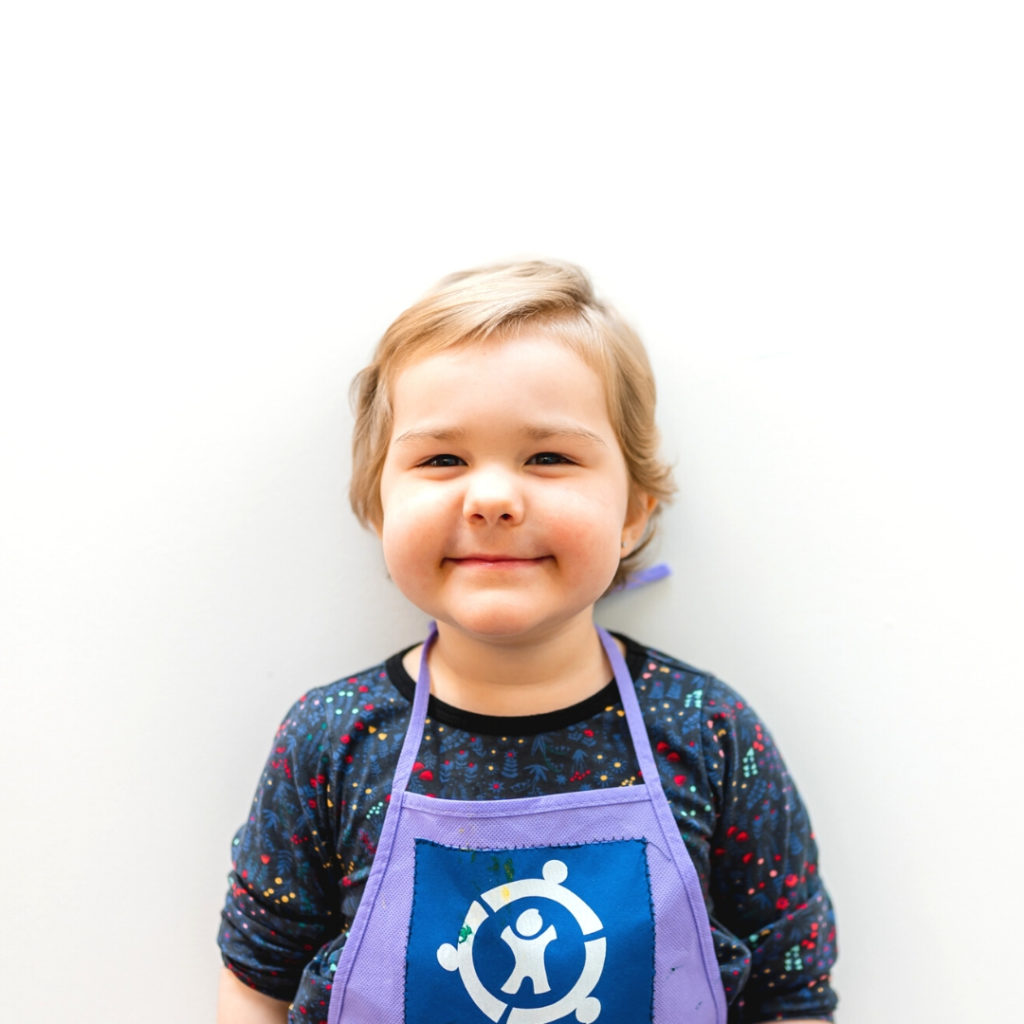Charlie is wearing a purple apron with the blue Connor's Heroes logo