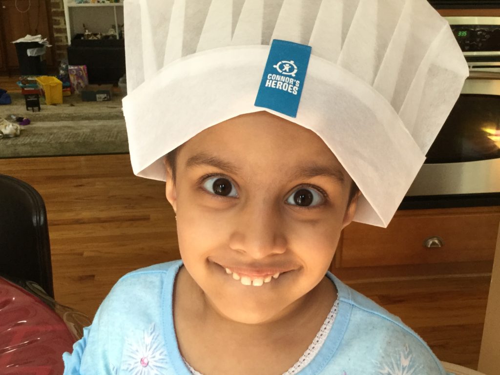 A child wearing a Connor's Heroes chef hat making a silly face