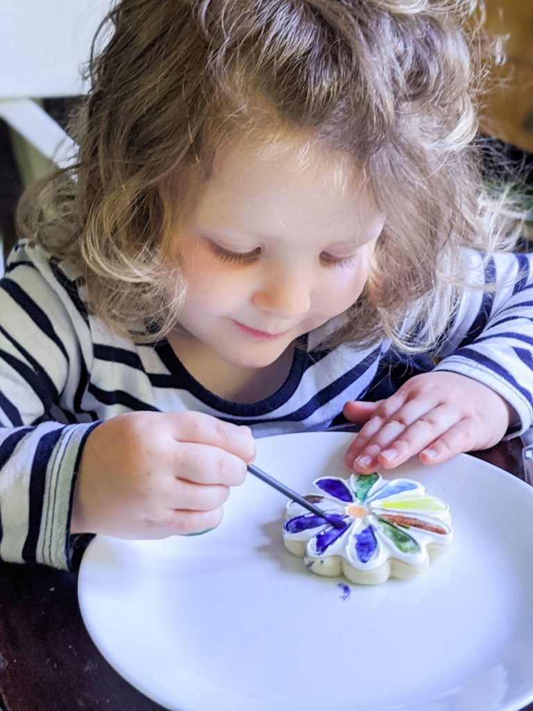 Child decorating a cookie shaped like a flower
