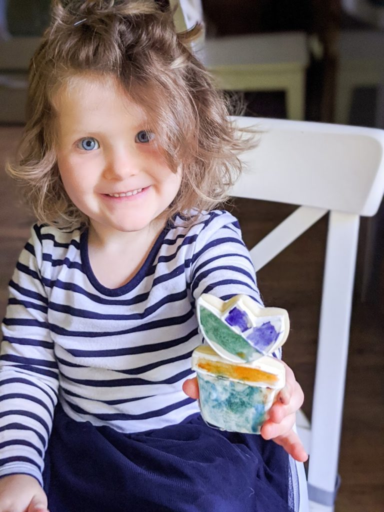 Child smiling and holding up a colorfully decorated cookie