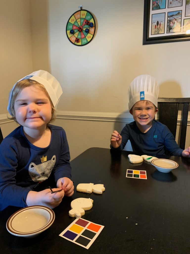 Two children wearing Connor's Heroes chef hats decorating cookies