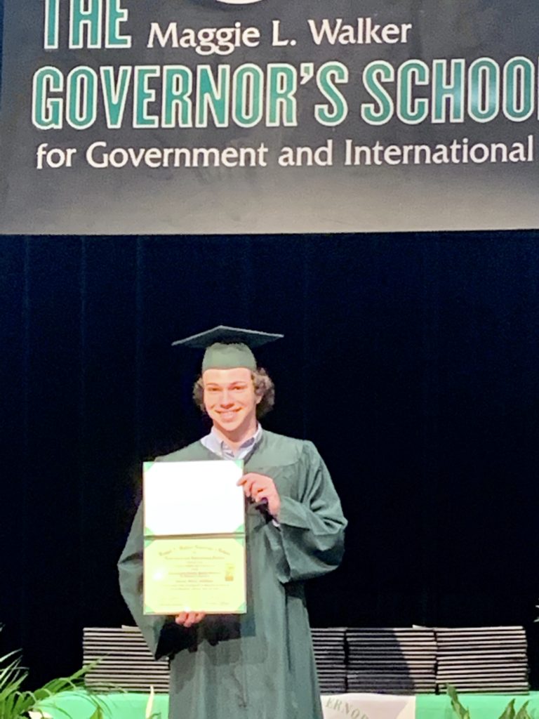 Connor standing with his high school diploma.