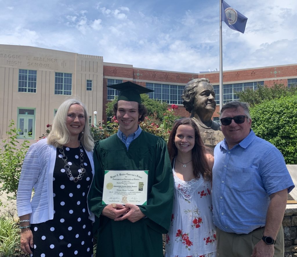 Group photo of Connor holding his high school diploma standing with his family