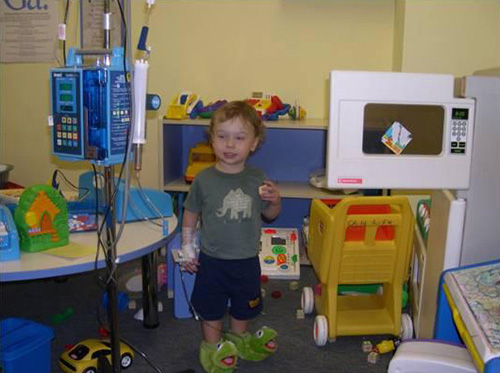 Toddler in a hospital room wearing Kermit slippers