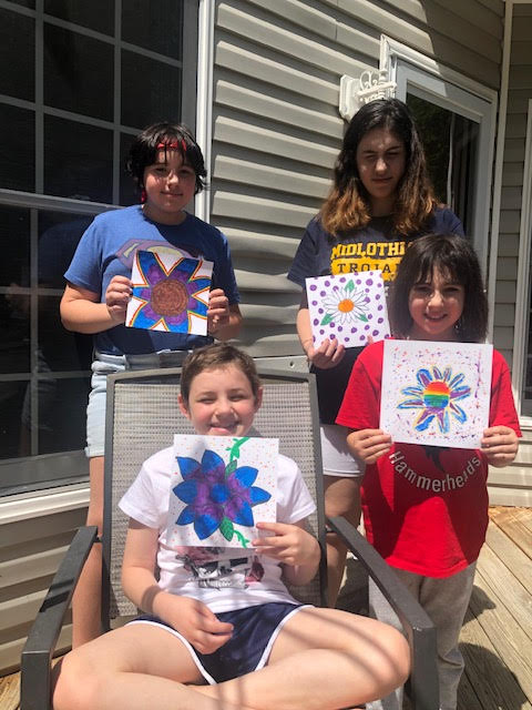 A family of four hold up the pictures they painted during the virtual art class hosted by Connor's Heroes