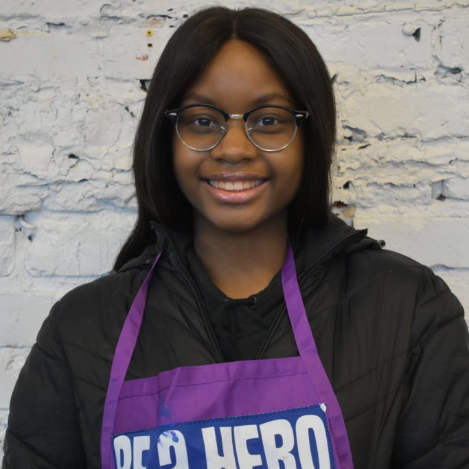 Teenager wearing glasses and an apron that reads 