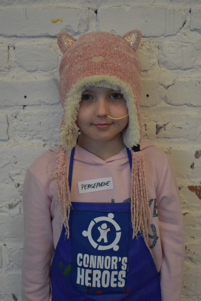 Child wearing a hat with cat ears and an apron with Connor's Heroes