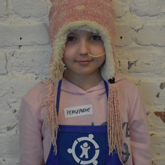 Child wearing a hat with cat ears and an apron with Connor's Heroes