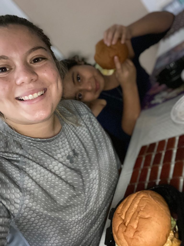 Parent and a child sitting together each eating a hamburger