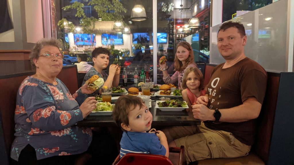 Parent, grandparent, three children and a baby sitting in a restaurant