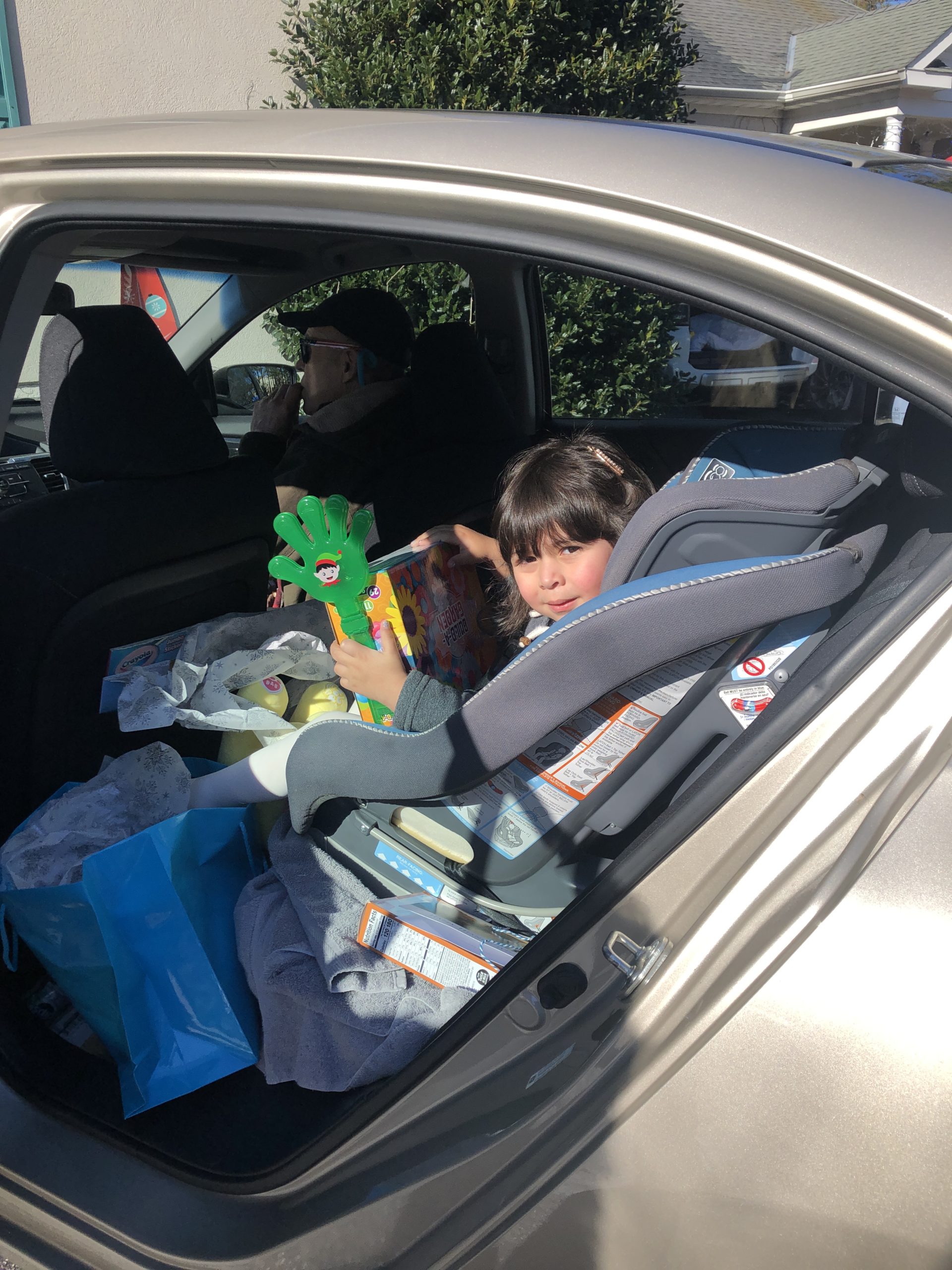 A girl in the back seat of a car holding holiday decorations
