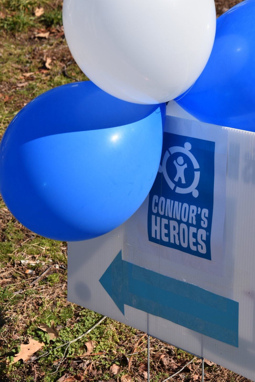 White and blue balloons with a sign for Connor's Heroes