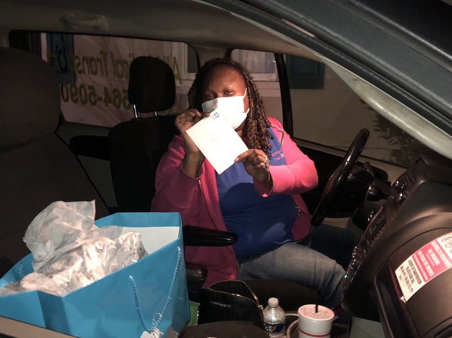 A woman in a car holding up an envelope