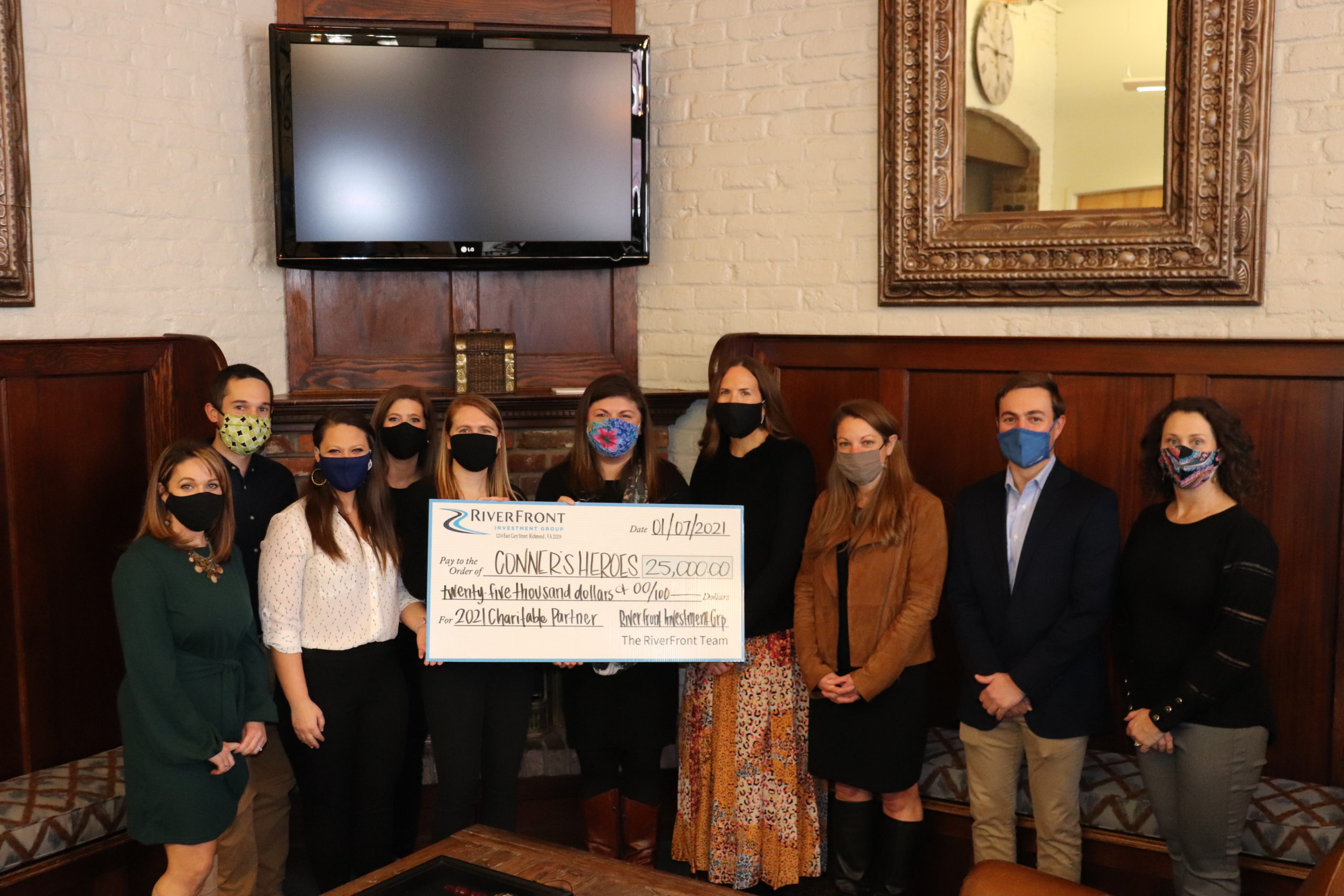 10 people standing together holding a check written out to Connor's Heroes for $25,000