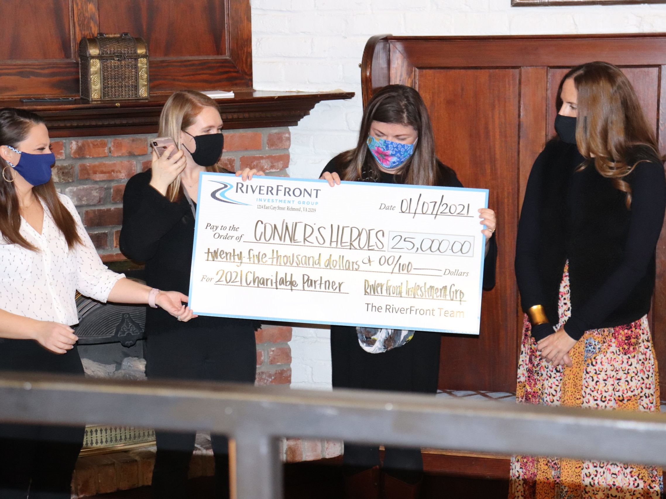 4 people standing together holding a check written out to Connor's Heroes for $25,000