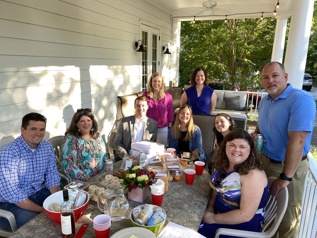 Image 9 people sitting outside around a table