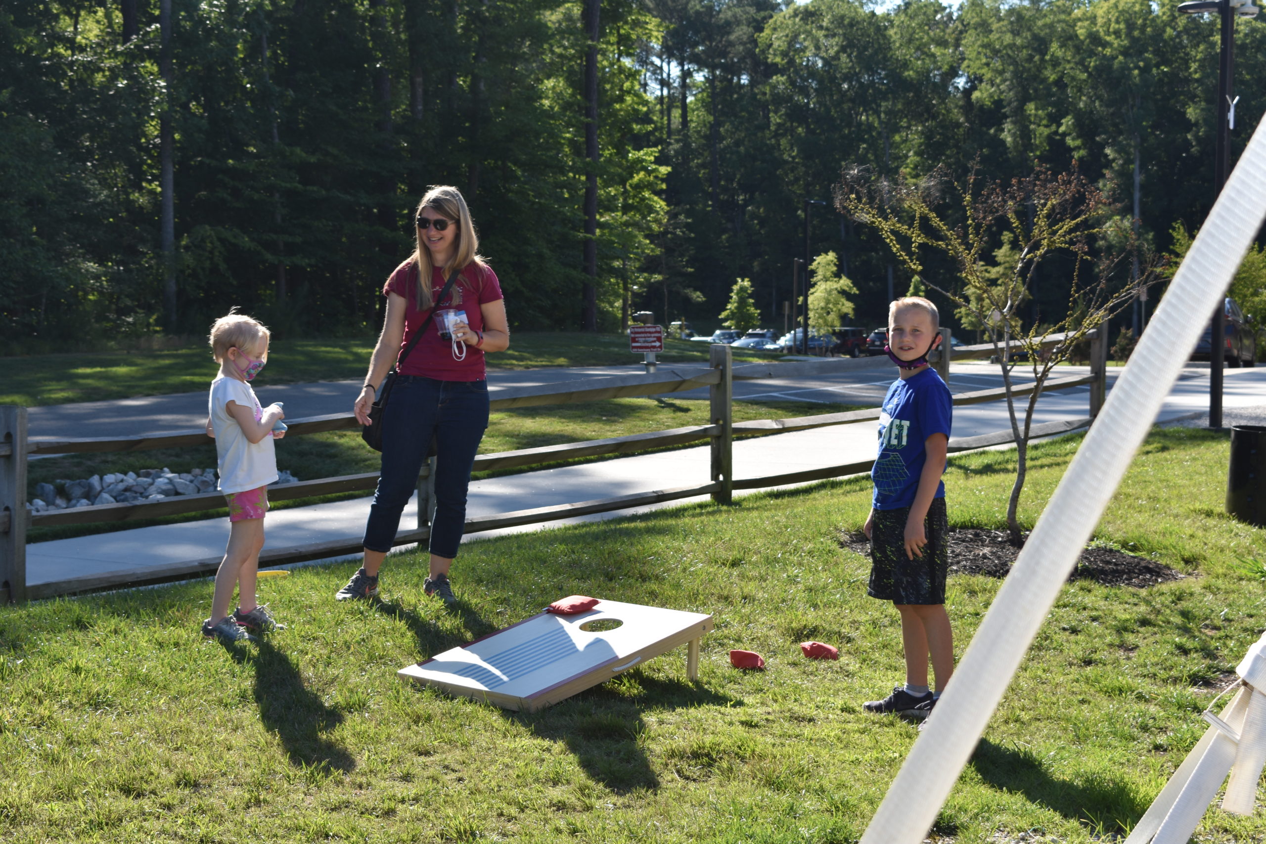Image a parent playing cornhole with two children