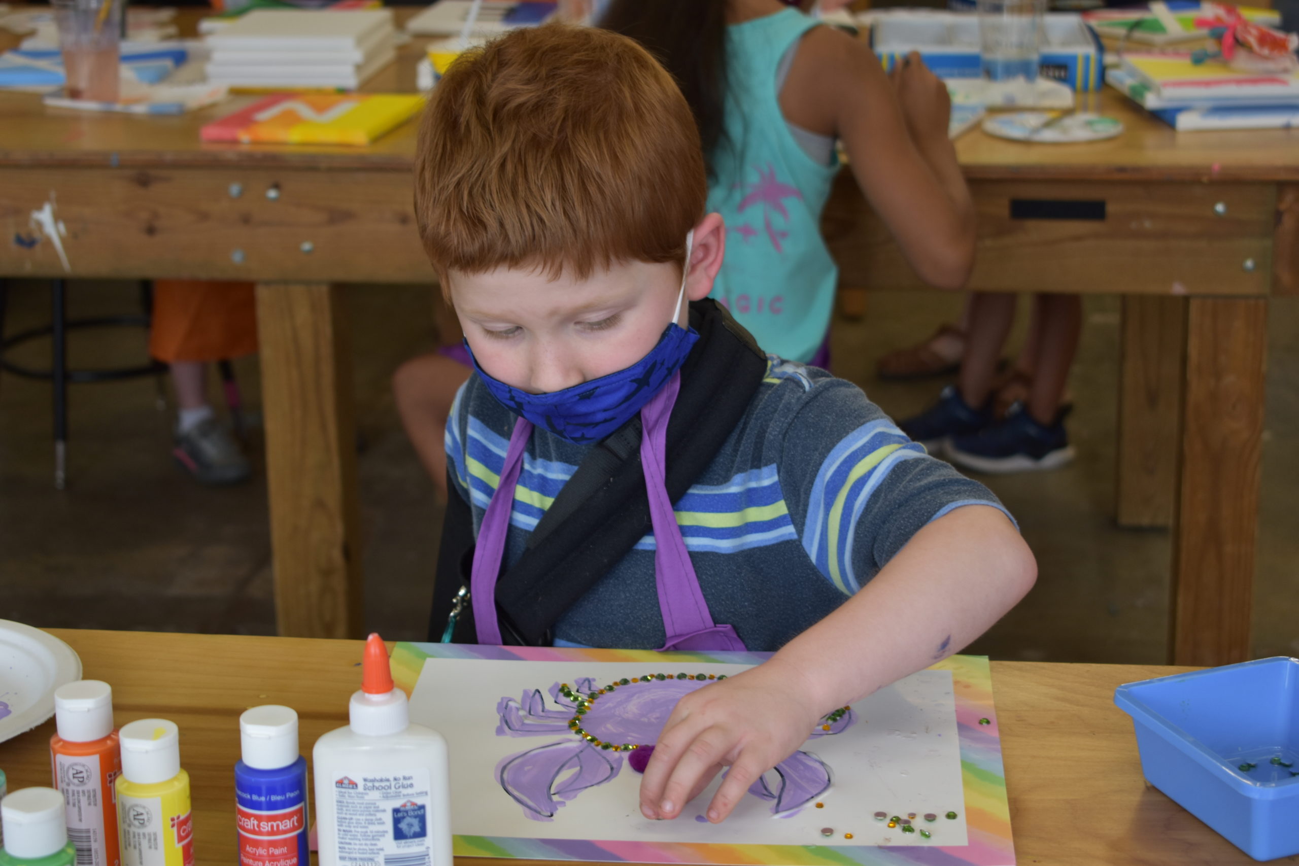 A child putting glitter on his painting of a crab