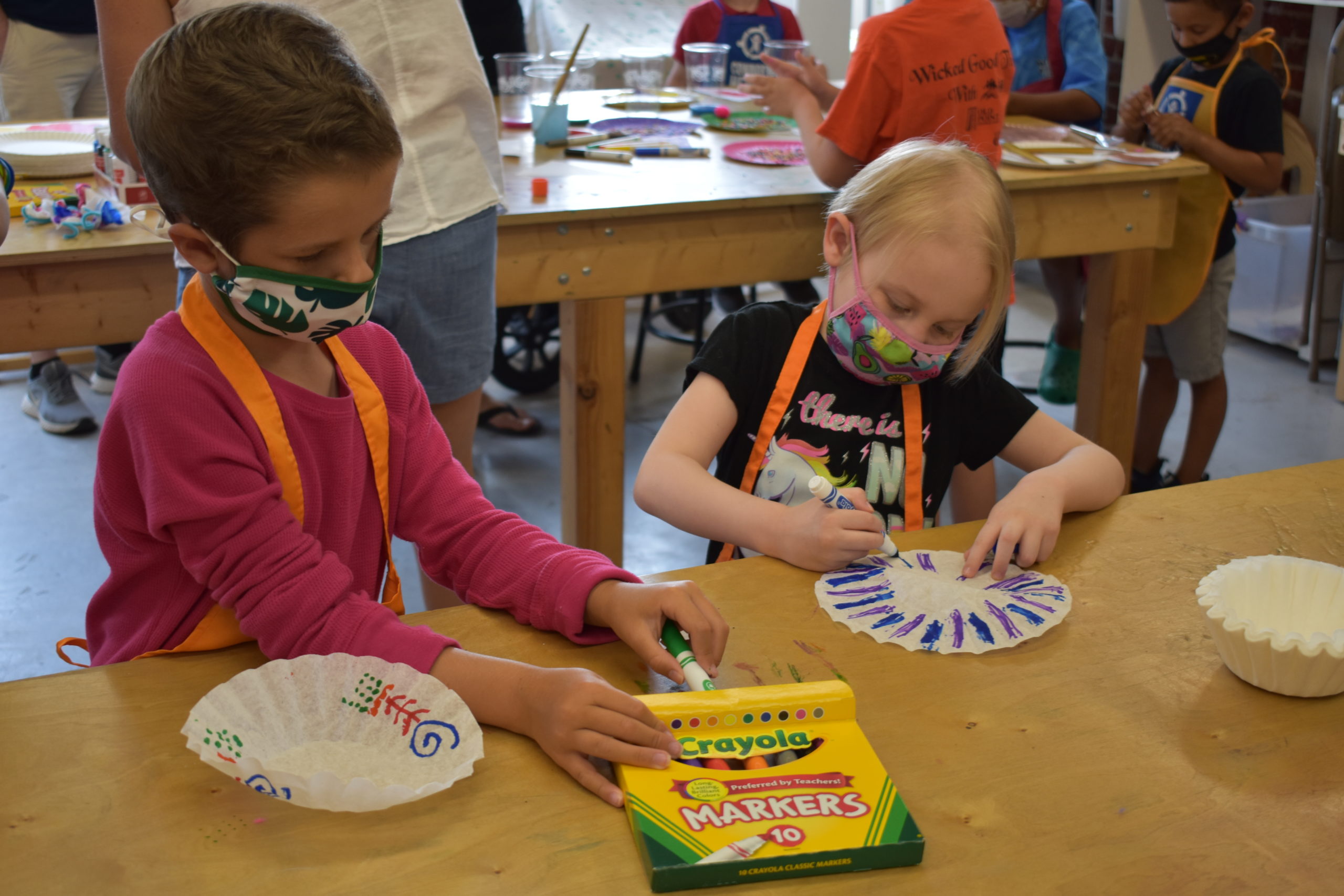 Two children using markers to color white coffee filters