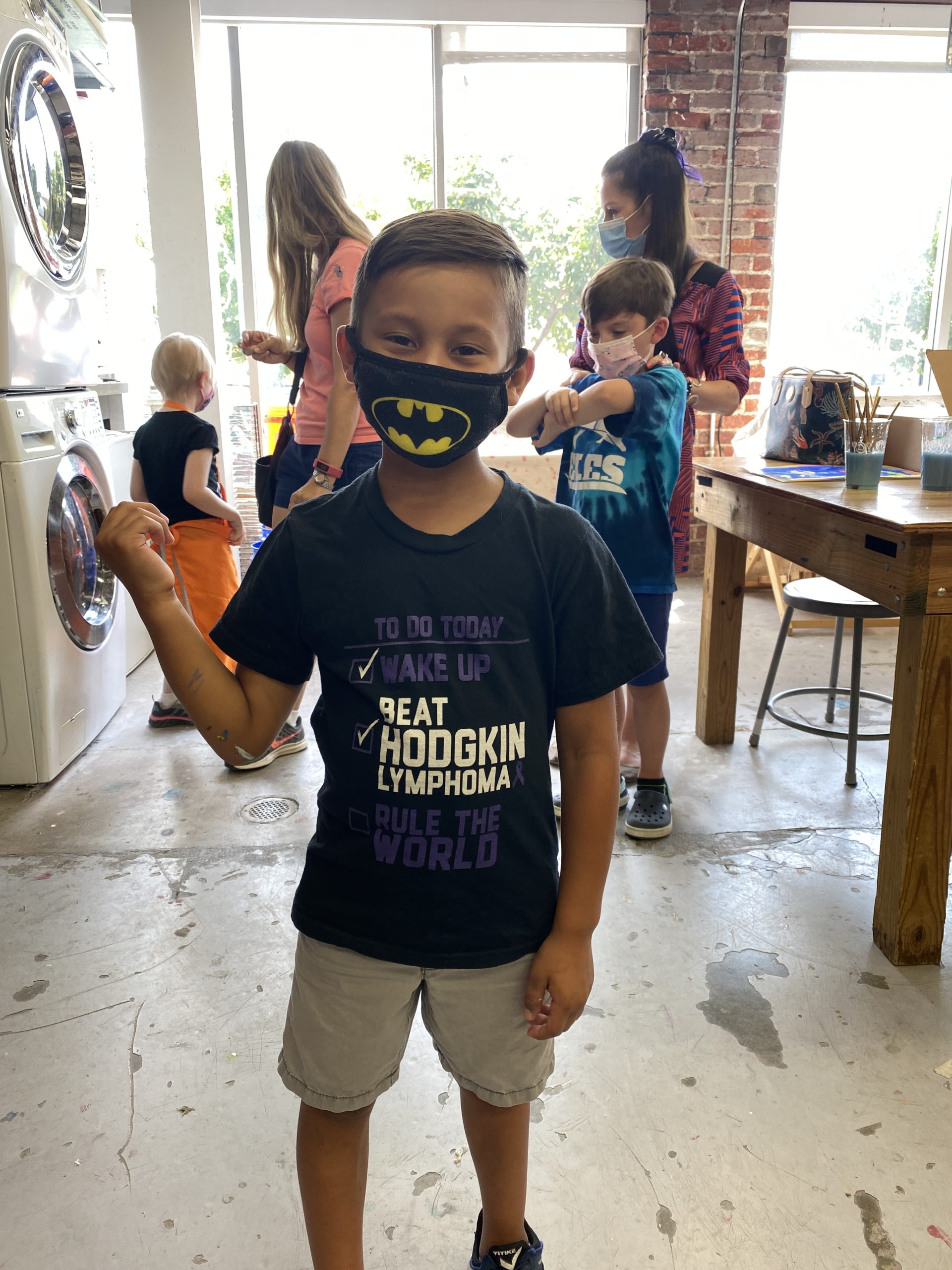 A child wearing a mask standing in an art studio