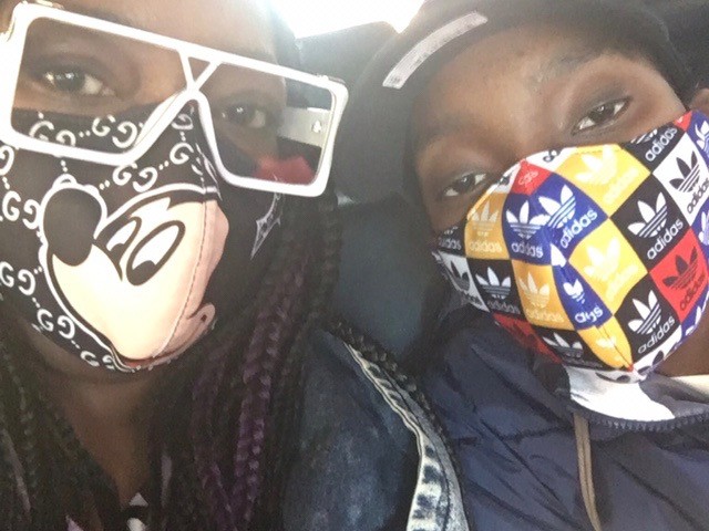 Image of a teenager wearing a mask sitting next to his mom who is wearing a mask