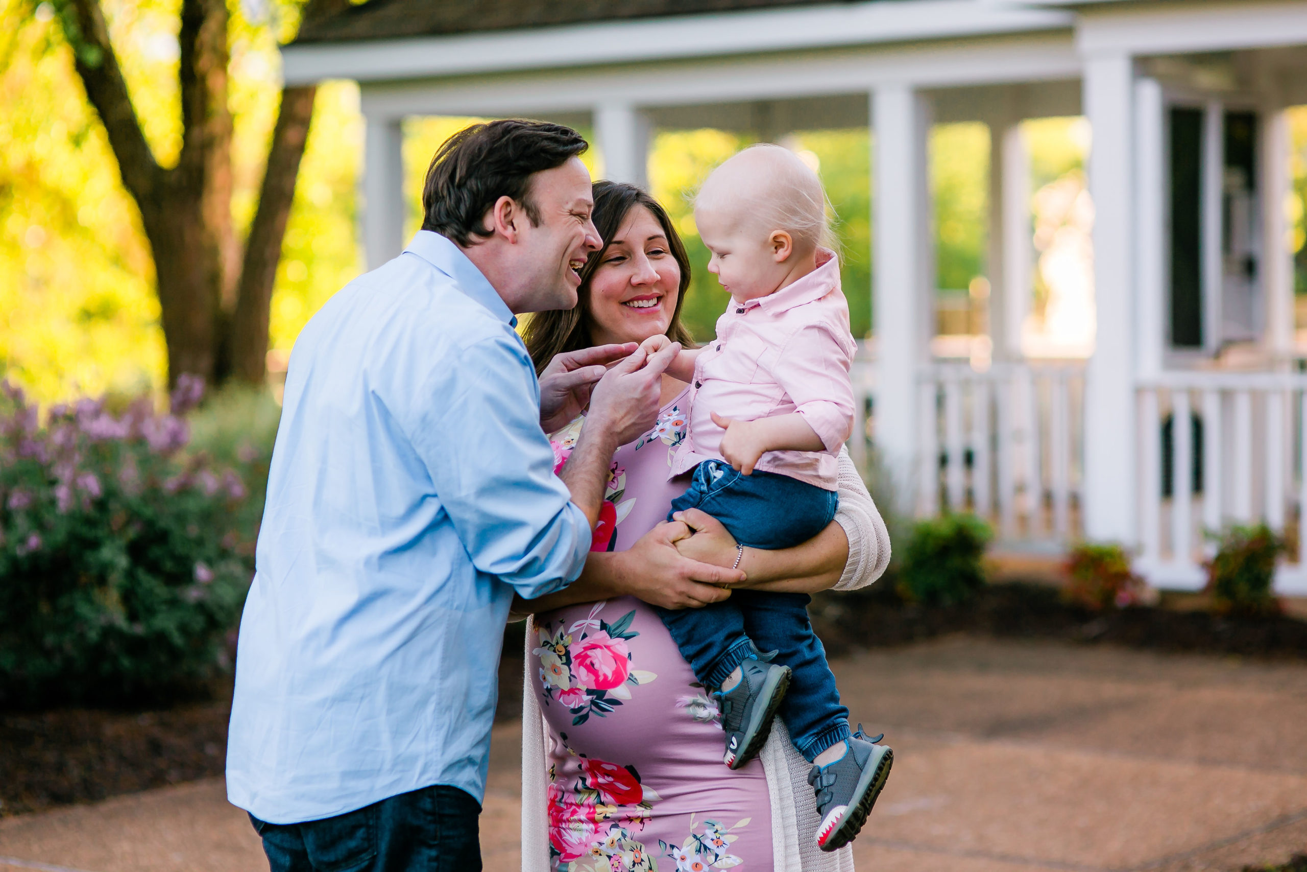 Image a pregnant mom holding her child with her husband standing beside her