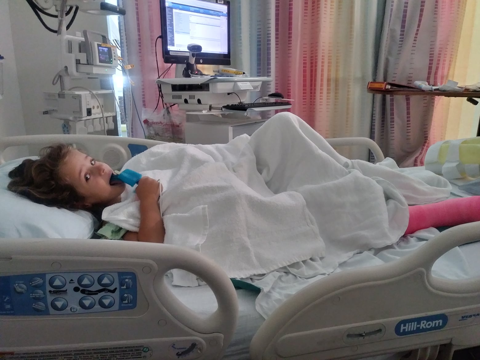 Image a child in a hospital bed eating ice cream