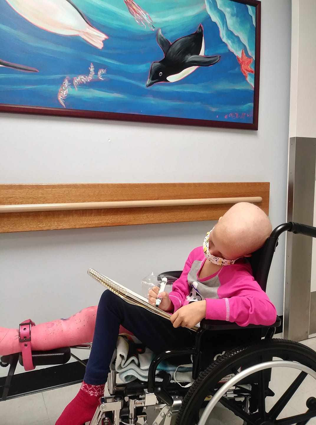 Image a child sitting in a wheelchair in a hospital