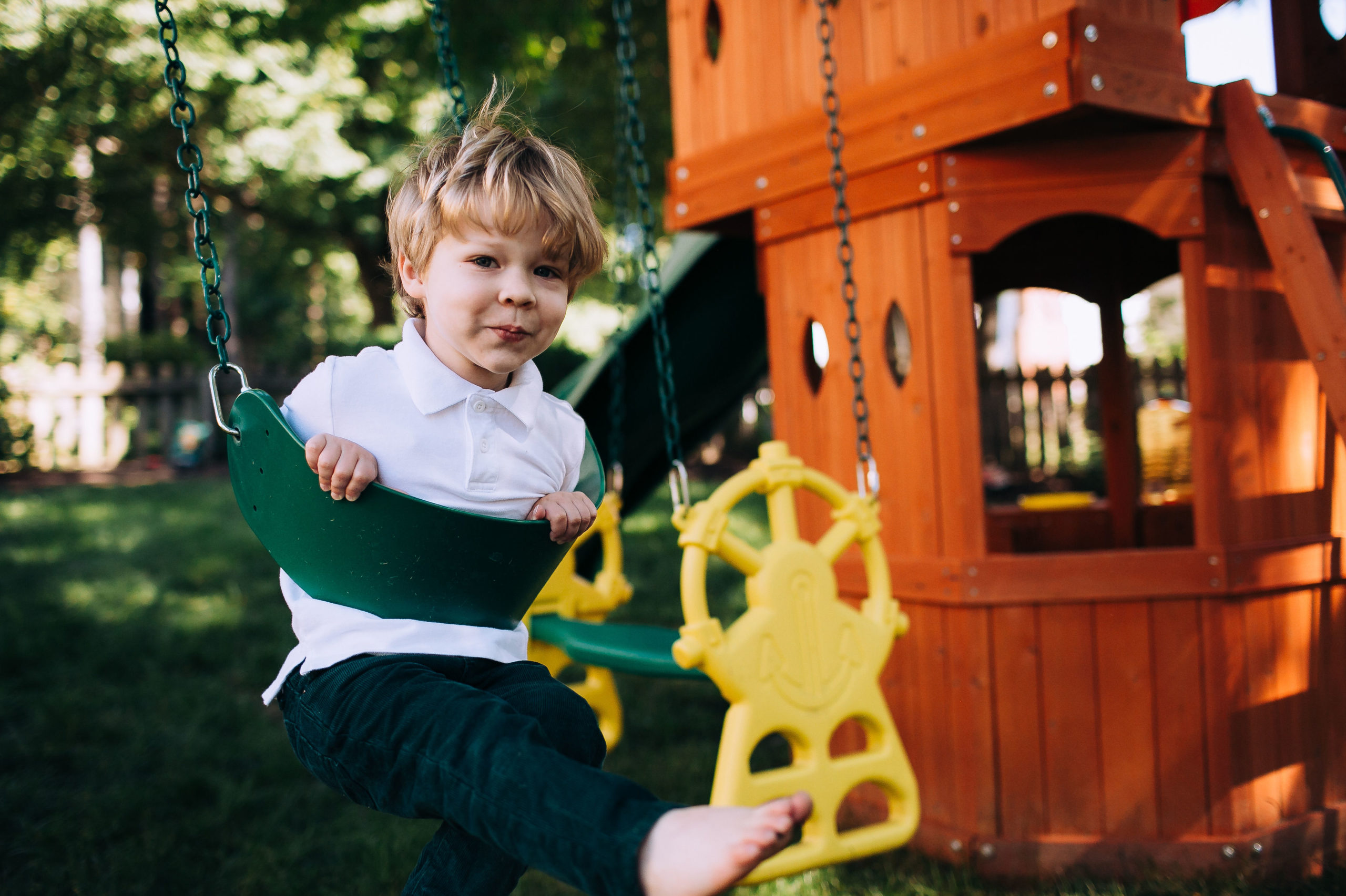 Image child sitting on a swing in backyard