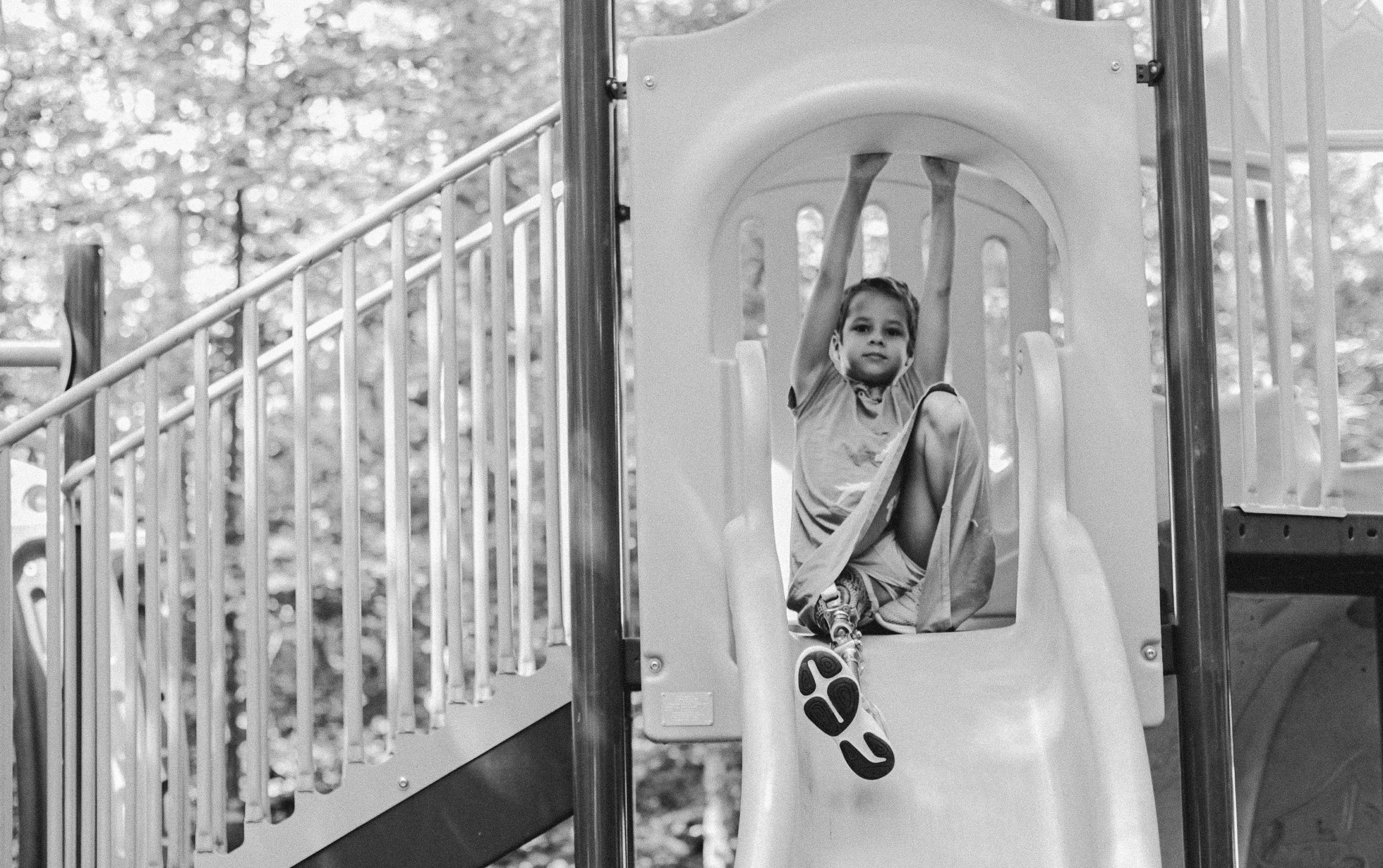 Image black and white photo of child on a slide