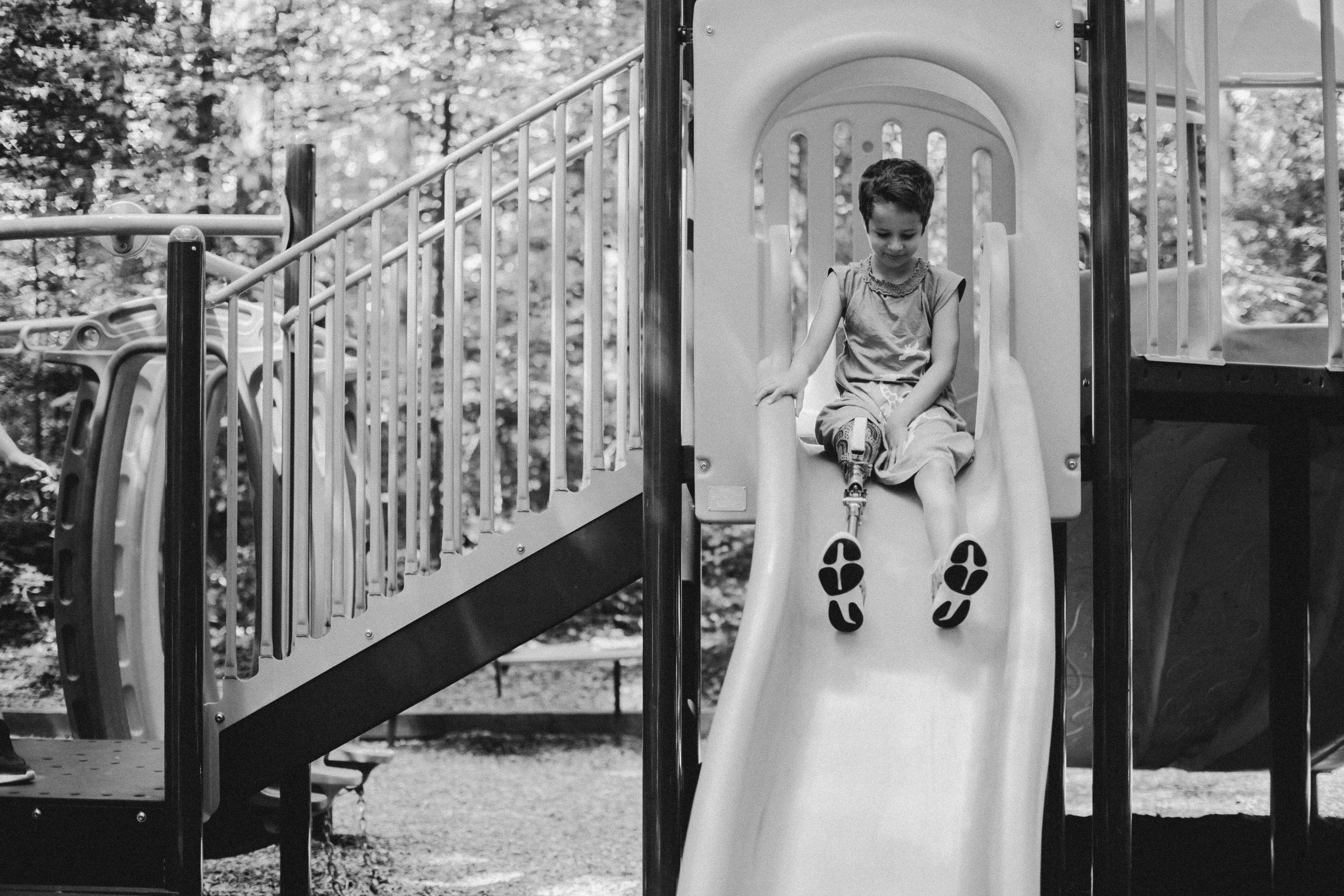 Image black and white photo of child sliding down a slide