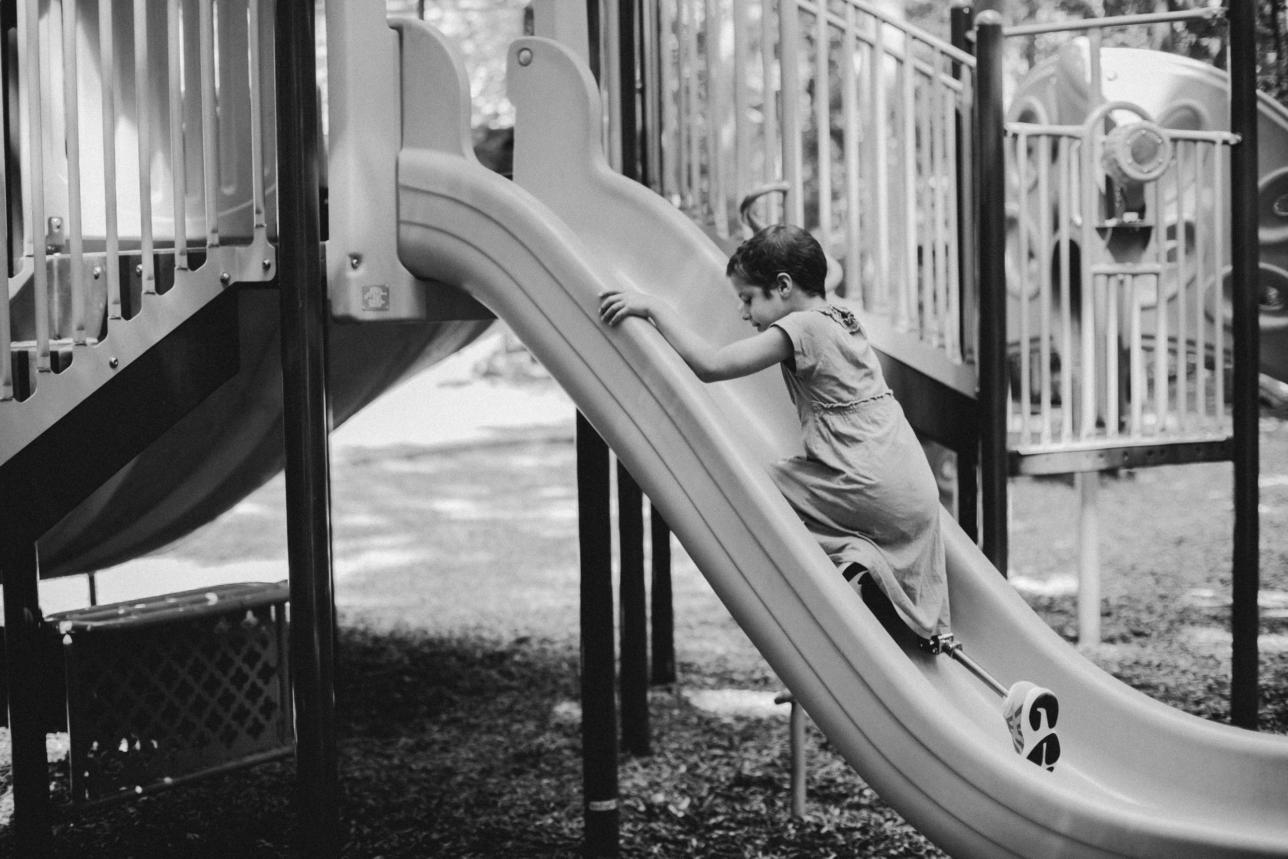 Image black and white photo of child climbing a slide